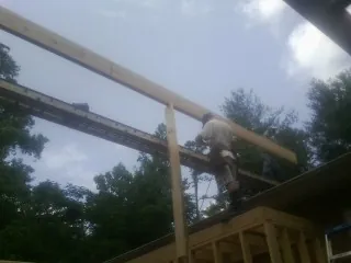 Carpenter setting a ridge beam over a new addition frame — Ice Dam Removal by Roofing Brothers in Fingerville