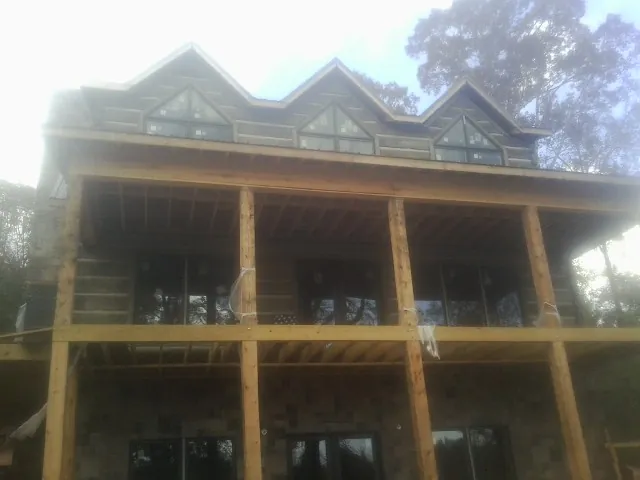 Dormers and porch framing on a large log home under construction — Roof Coating work by our crew in Fingerville