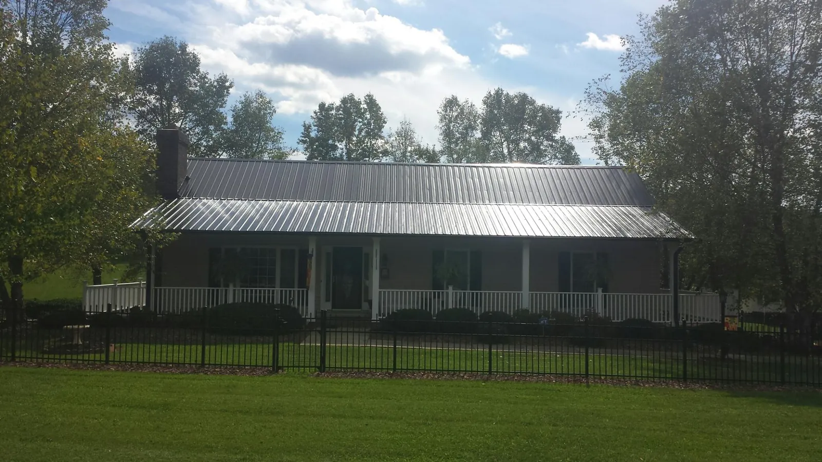 Gray metal roof on a brick ranch with a full width front porch — Gutter Guard Installation work by our crew in Fingerville