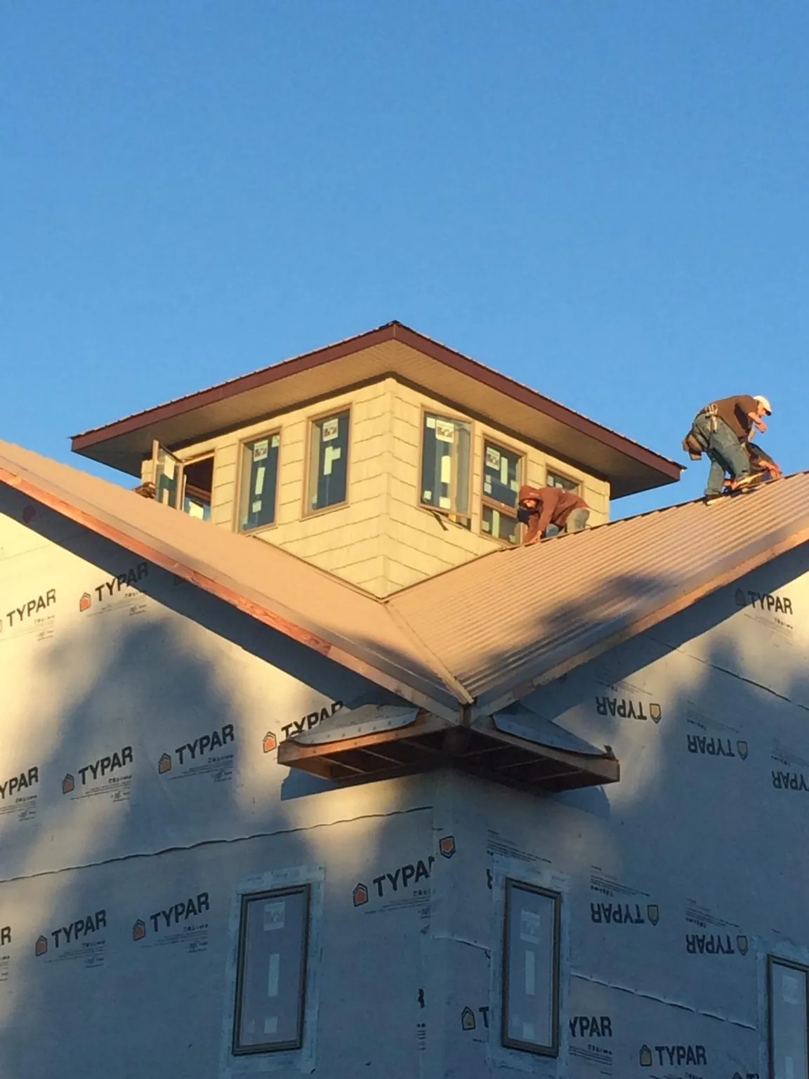 Roofers working around a rooftop cupola on a new metal roof at sunset — Roof Waterproofing in Fingerville by Roofing Brothers